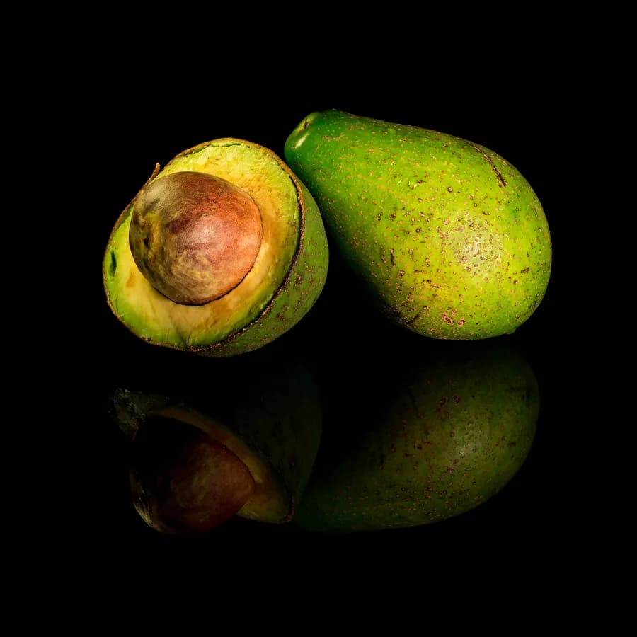 Avocados, one of them halved to the stone