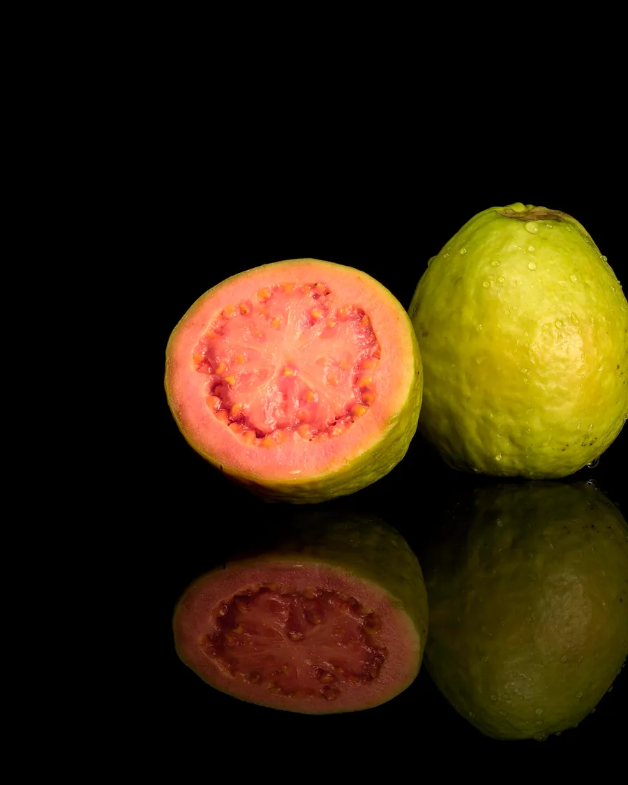A pink-fleshed guava cut beside a whole one
